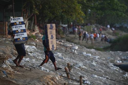 FLUJOS INCESANTES. Mientras personal de Migración (al fondo) revisa, ayer, documentos a viajeros que cruzan el río Suchiate desde Tecún Umán, Guatemala, trabajadores alistan mercancía para enviarla al país centroamericano.