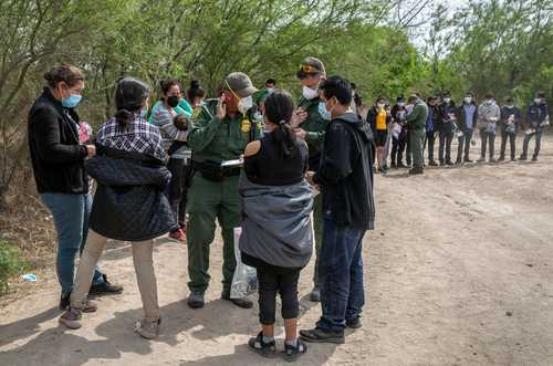 En Hidalgo, Texas, agentes de la Patrulla Fronteriza interrogan a varias familias que acaban de cruzar el río Bravo. En primer plano, varios menores no acompañados, que serán transportados a instalaciones para migrantes, de acuerdo con la política de no expulsarlos.