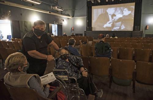 A la espera de ser vacunadas contra el Covid-19, en Rosario, Argentina, estas personas ven un filme del actor inglés.