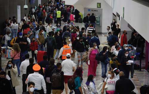 A las cuatro de la mañana de ayer, vacacionistas hacen filas y no respetan la sana distancia en el área de check in de vuelos nacionales en la Terminal Uno del AICM.
