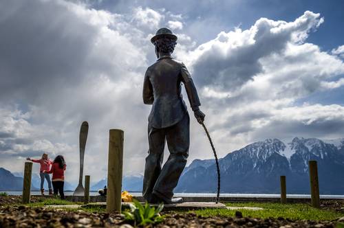 Imagen en el lago Lemán en Vevey muestra a turistas tomando fotografías bajo densas nubes junto a una estatua de El vagabundo, el personaje más memorable en pantalla del actor británico Charles Chaplin.
