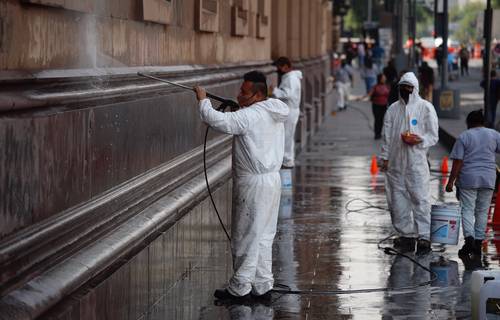 Trabajadores limpian las paredes del Palacio Postal, en la calle Tacuba del Centro Histórico de la Ciudad de México.