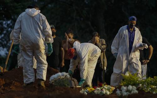 Enfundados en trajes protectores, empleados de un cementerio en Sao Paulo entierran un cadáver ante los lamentos de familiares. Brasil, uno de los países más afectados por la emergencia de salud, alcanzó un total de 370 mil fallecidos, con promedio diario de alrededor de 3 mil decesos.