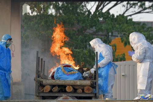 En un crematorio al aire libre en Bangalore, al sur de India, familiares realizan ritos finales para una víctima que murió por el coronavirus.