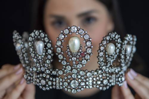 Durante una demostración en Ginebra, Suiza, donde tendrá lugar la subasta el 11 de mayo, una empleada de Sotheby’s muestra una tiara de diamantes y perlas que data de la segunda mitad del siglo XIX. Procedente de la Casa de Saboya, probablemente la joya fue entregada a Maria Vittoria dal Pozzo en 1867 como regalo de bodas con motivo de su enlace con Amedeo de Saboya, duque de Aosta, posteriormente elegido rey de España como Amadeo I (1870-1873). De acuerdo con la información del catálogo de la casa de subastas, la pieza permaneció en la familia más de 150 años y se cree que fue diseñada por Musy Padre e Figli, joyería de la corte de Turín, y una de las orfebrerías más antiguas de Europa. Se estima que el precio de venta oscilará entre un millón y un millón y medio de dólares.