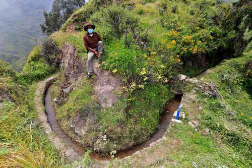 Un campesino de la comunidad San Pedro de Casta sentado junto a una sección de la red de canales de piedra que surca las laderas de los cerros.