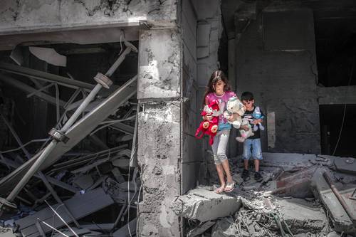 Niños palestinos rescatan juguetes de su casa en la torre Al Jawhara, en la ciudad de Gaza, devastada en un ataque aéreo israelí.