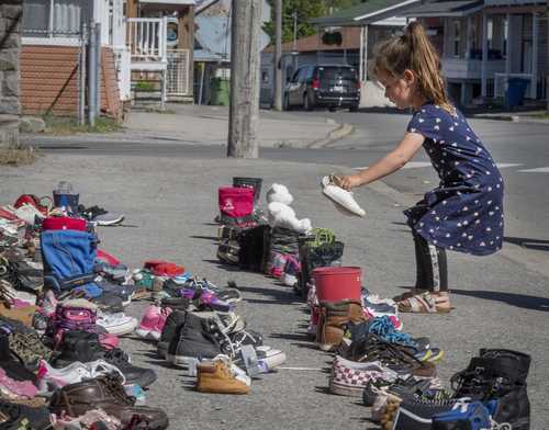 Una niña coloca sus zapatos frente a la iglesia de San Francisco Javier en Kahnawake, Quebec, en memoria de los 215 pequeños hallados en la antigua escuela.