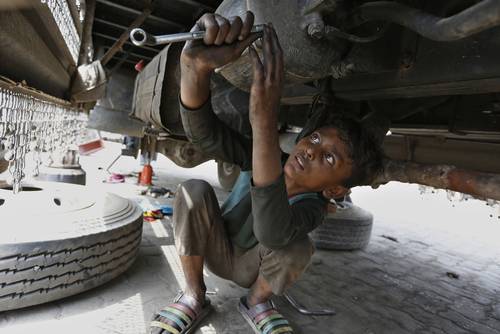 Un pequeño labora en un taller de reparación de automóviles en Lahore, Pakistán.
