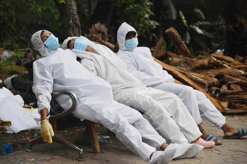 Personal de una ambulancia que traslada enfermos de Covid-19 descansa después de sus labores afuera de crematorio de Guwahati, India.