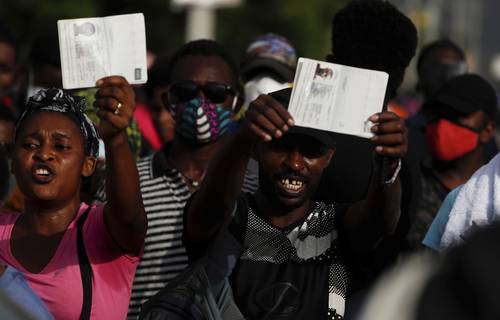 Con sus pasaportes, haitianos piden refugio ante la embajada de Estados Unidos en Puerto Príncipe.