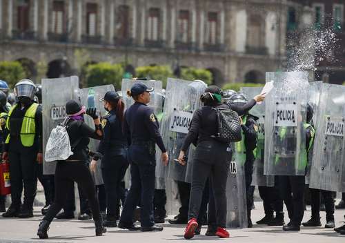 Mujeres que marcharon ayer al Zócalo lanzaron agua a las policías, que mantuvieron un escudo inmóvil en el primer cuadro.