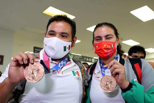  Luis Álvarez y Alejandra Valencia muestran el bronce conseguido en Tokio a su llegada al aeropuerto capitalino. Foto Roberto García Ortiz