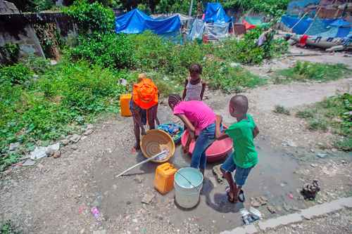 Niños haitianos lavan ropa y acarrean agua en un campamento de damnificados por el terremoto en Les Cayes.