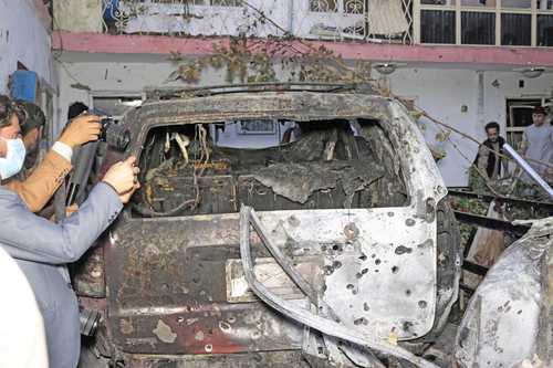 Un reportero afgano toma fotografías de un vehículo que estando en el patio de una casa fue alcanzado por el ataque con dron lanzado por el ejército de Estados Unidos ayer en Kabul.
