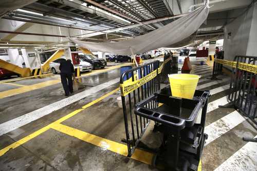 Con lonas desvían hacia tambos los escurrimientos de agua en el estacionamiento principal del Palacio Legislativo.