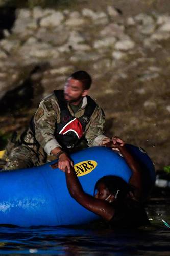 Un agente de la Patrulla Fronteriza ayuda a un migrante haitiano en el río Bravo. Los temores de deportación aumentaron ayer entre los migrantes tras la repentina llegada de decenas de policías al lugar.