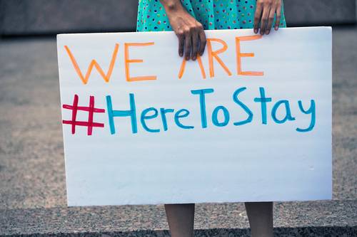 “Estamos aquí para quedarnos”, se lee en el cartel de un dreamer que asistió a una movilización en Austin, Texas, en imagen de archivo.