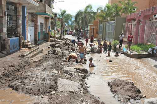 Niños de la colonia Ojo de Agua, municipio de Tla-quepaque, Jalisco, juegan en los charcos formados tras la intensa lluvia que cayó ayer. Una mujer de 18 años murió ahogada al ser arrastrada por la corrien-te; su cuerpo fue hallado en el canal de Las Pintas. En Chapala, Jocotepec, Ajijic y Cosalá deslaves afecta-ron viviendas.