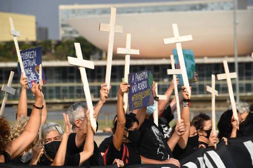 Manifestantes acudieron ayer con cruces en mano al palacio de gobierno en Brasilia para protestar por el récord de muertes.