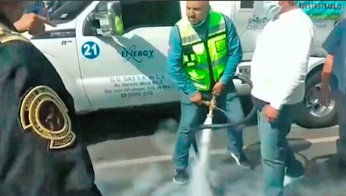 Un gasero abre la manguera de la pipa para amagar a policías cuando intentaron retirar los camiones que bloquearon Eje 5 Sur e Insurgentes Sur, frente a la Secretaría de Energía, en protesta por el alza de precios del gas LP que implicaría la reducción de sus comisiones.