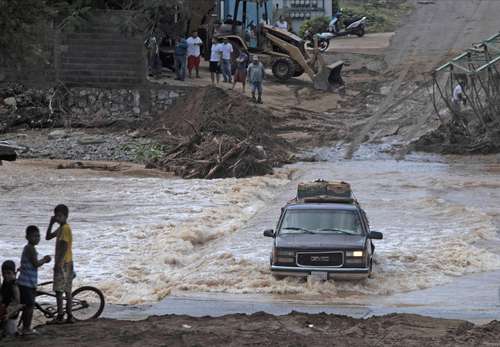 Un vehículo atraviesa una carretera inundada después del pasó del huracán Rick en el poblado de Infiernillo, municipio de Arteaga, Michoacán, donde las fuertes lluvias provocaron el colapso de un puente peatonal.