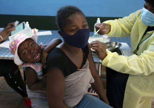 Una mujer con su hijo a cuestas es vacunada en Johannesburgo, Sudáfrica, el país más castigado de África por el Covid-19.