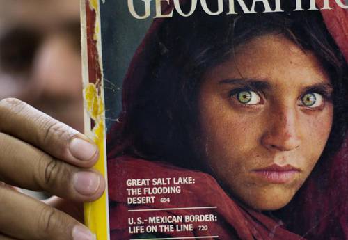 En imagen de archivo del 26 de octubre de 2016, el paquistaní Inam Khan, dueño de una librería, muestra una copia de una revista de National Geographic con la fotografía de la refugiada afgana Sharbat Gulla, en Islamabad, Pakistán.