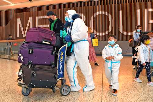 En el aeropuerto de Melbourne, en Australia, que registró ya sus primeros casos de la nueva variante de Covid-19, viajeros usan un equipo de protección especial.