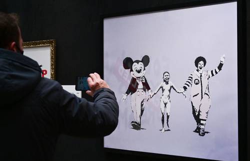  The Word of Banksy: The Immersive Experience, en la Estación Central de Milán, Italia, incluye recreaciones realizadas por jóvenes artistas europeos sobre fondos que imitan el entorno urbano original en el que las pintó el grafitero. Sobre estas líneas, un hombre captura una foto del mural Napalm (Can't Beat that Feeling) Foto Afp