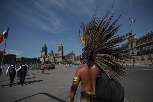 Con mochila al hombro, un danzante conchero se dirige al punto de reunión con sus compañeros en el Zócalo.