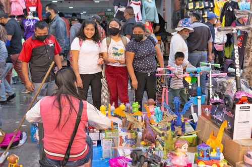 Decenas de personas comenzaron a acudir al Centro Histórico en busca de los regalos de Nochebuena. En esta imagen, integrantes de una familia regatean en un puesto ambulante de juguetes de plástico en la calle Corregidora.