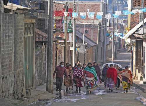 Pobladores de la comunidad de Comachuen, municipio de Nahuatzen, Michoacán, caminan por una calle de la localidad, la cual subsiste principalmente de las remesas que sus familiares envían desde Estados Unidos. Según Porfirio Gabriel, quien se encarga de organizar a los trabajadores migrantes, el pueblo estaría “muerto” si no contara con esos ingresos.