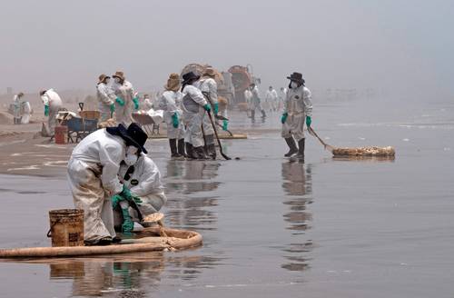 Equipos de limpieza de crudo derramado en la playa Cavero, en El Callao, Perú.