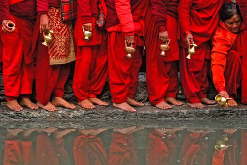 Devotos esperan en la fila para llenar su vasija con agua del río Bagmati en el templo Pashupati-nath, durante el festival Swasthani, que dura un mes, en Katmandú, capital de Nepal.
