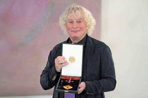 El director de orquesta Simon Rattle sostiene la Orden al Mérito de la República Federal de Alemania tras recibirla de manos del presidente de esa nación, Frank-Walter Steinmeier.