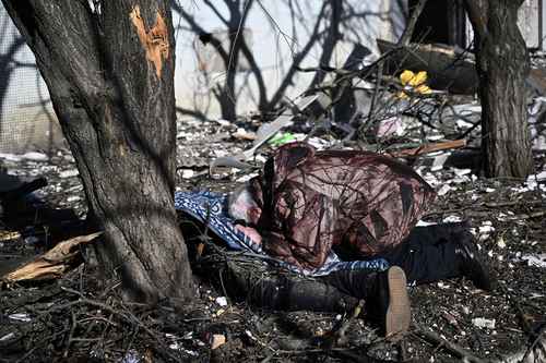 Un hombre identifica el cadáver de un pariente afuera de un edificio destruido después de los bombardeos en Chuguiv, en el este de Ucrania. Foto Afp