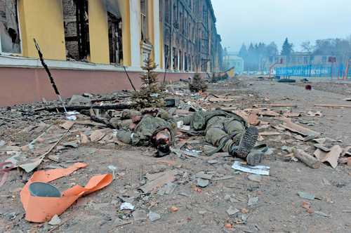 Los cuerpos de dos soldados rusos yacen al lado de una escuela destruida luego de los combates en la ciudad de Jarkov, cerca de la frontera.