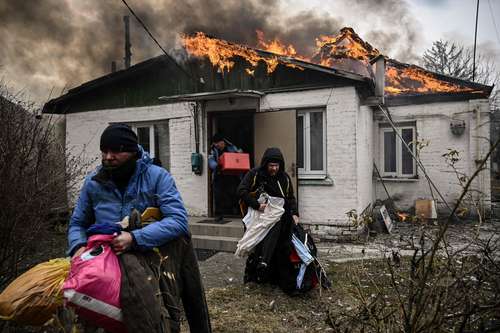  En Irpin, una ciudad cercana a la capital de Ucrania, habitantes sacan pertenencias de sus casas, en llamas a causa de un bombardeo. Foto Afp