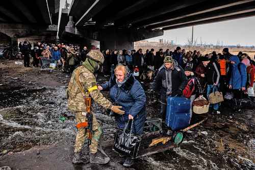 Un soldado ucranio auxilia a civiles a abandonar Irpin a través de un puente colapsado por los bombardeos.