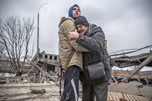 Un integrante de las Fuerzas de Defensa Territorial ucranias abraza a un residente que abandona su ciudad natal tras el bombardeo de la artillería rusa en Irpin, en las afueras de la capital Kiev.