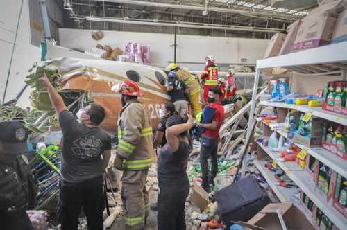 Elementos de Protección Civil de Morelos retiran los escombros de la aeronave que se estrelló en una tienda Bodega Aurrerá.