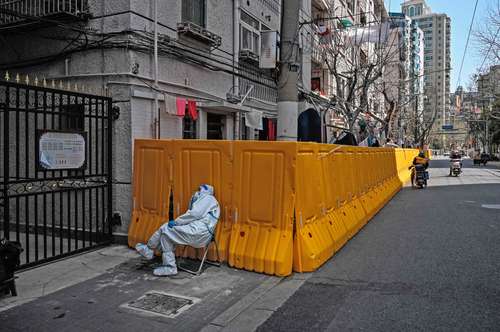  Un trabajador vigila la entrada de un barrio como medida para contener el covid-19 en el distrito de Jing'an, en Shanghái. Foto Afp