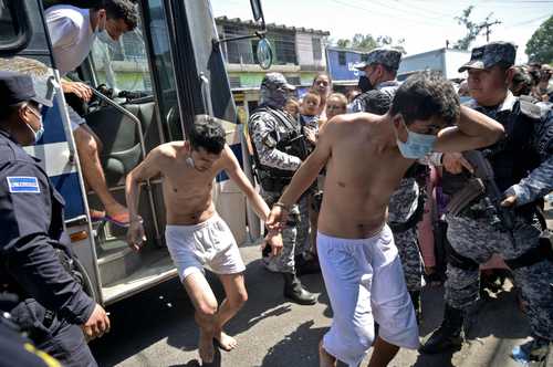 Detenidos que son acusados de tener vínculos con pandillas en El Salvador son escoltados por la Policía Nacional Civil durante el estado de emergencia decretado por el gobierno de Nayib Bukele.