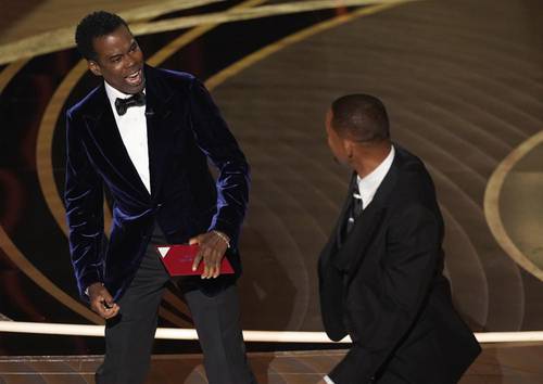El cómico Chris Rock (izquierda) reacciona tras ser golpeado por Will Smith en el escenario del teatro Dolby, antes de presentar el premio a mejor documental en los Óscar.