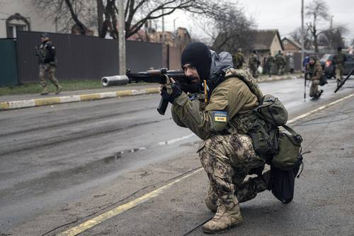 Un militar ucranio protege la retirada de sus compañeros, quienes revisaron cuerpos tirados en la calle en busca de minas, en un suburbio de Kiev.
