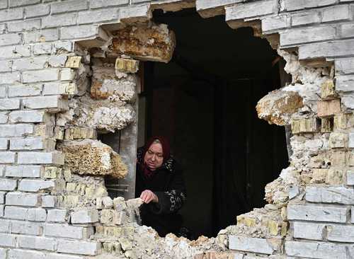 Una mujer identificada como Nadiya, residente en el pueblo de Zalissya, noreste de Kiev, muestra, ayer, un agujero en una casa tras un bombardeo.