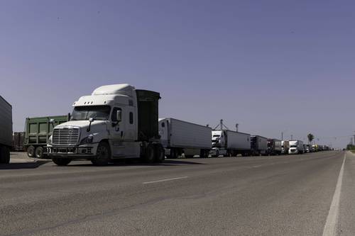 Cientos de camiones comerciales esperan en fila para cruzar el puente Progreso que une a Texas con Tamaulipas.