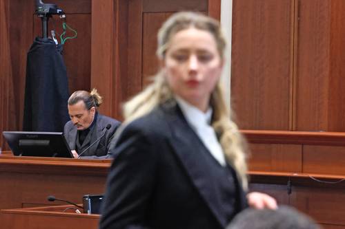 Amber Heard habla con sus abogados, y Johnny Depp, en el estrado, el 21 de abril.