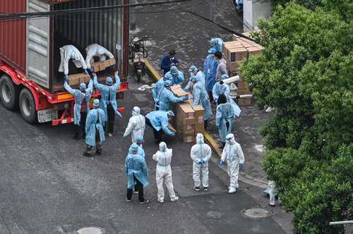 En un distrito de Shanghái en cuarentena, trabajadores descargan cajas. En China el rebote ha disminuido, informan autoridades.